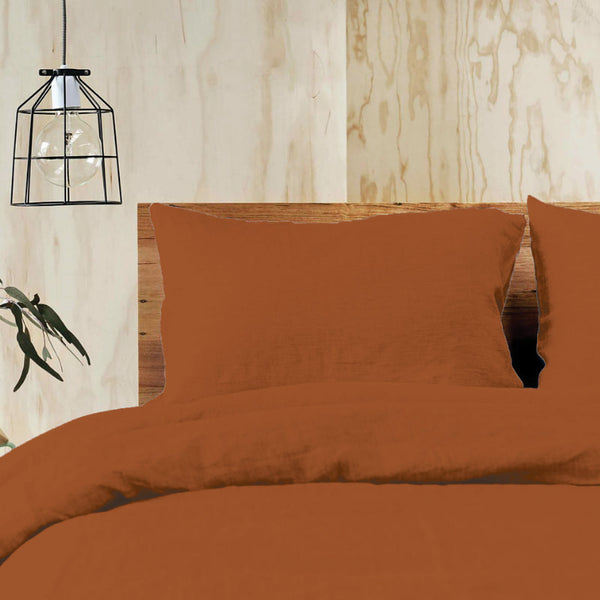 A bed adorned with luxurious terracotta quilt cover set, creating a warm and elegant atmosphere in the bedroom.