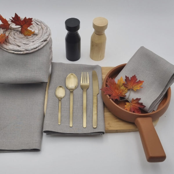 A dining table set with elegant Venice grey linen napkins, spoons, and forks, showcasing sophistication and practicality for any occasion.