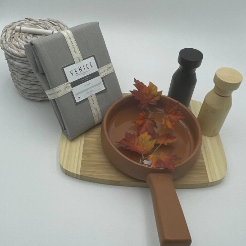 Packaging details of Venice grey linen napkins accompanied by a wooden tray and kitchen things, perfect for an elegant table arrangement.