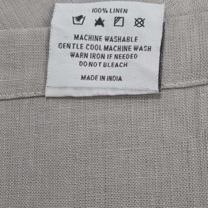 Back tag details on Venice grey linen napkin, showcasing practicality for effortless garment care.