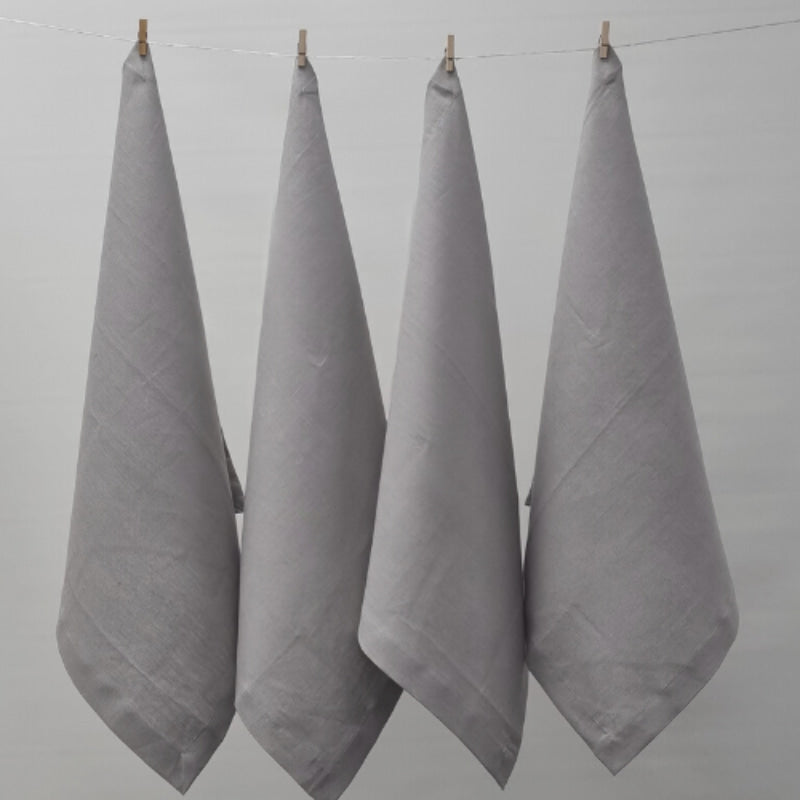 Four grey napkins hanging on a clothesline, exemplifying elegance and versatility in home textiles.