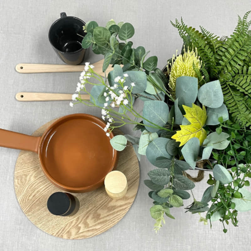 A table adorned with a pot of plants and kitchen things,  featuring a sophisticated RANS Venice Linen Grey Tablecloth.