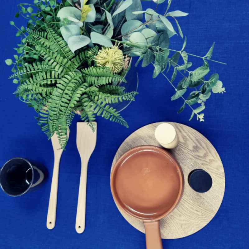 A table adorned with a pot of plants and kitchen things,  featuring a sophisticated RANS Venice Linen Indigo Tablecloth.