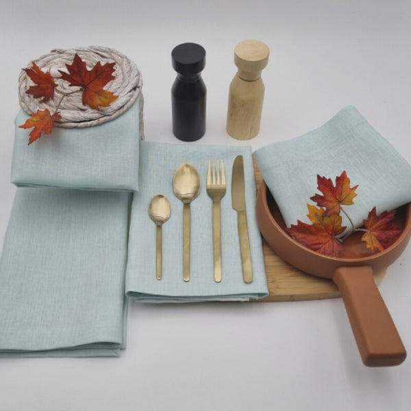 A dining table set with elegant Venice mist linen napkins, spoons, and forks, showcasing sophistication and practicality for any occasion.