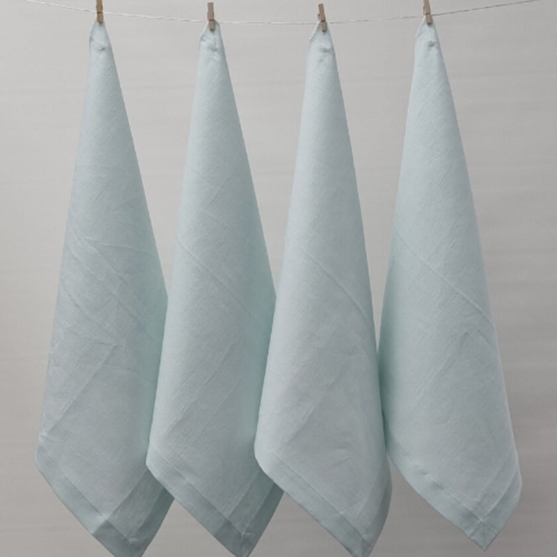 Four mist napkins hanging on a clothesline, exemplifying elegance and versatility in home textiles.