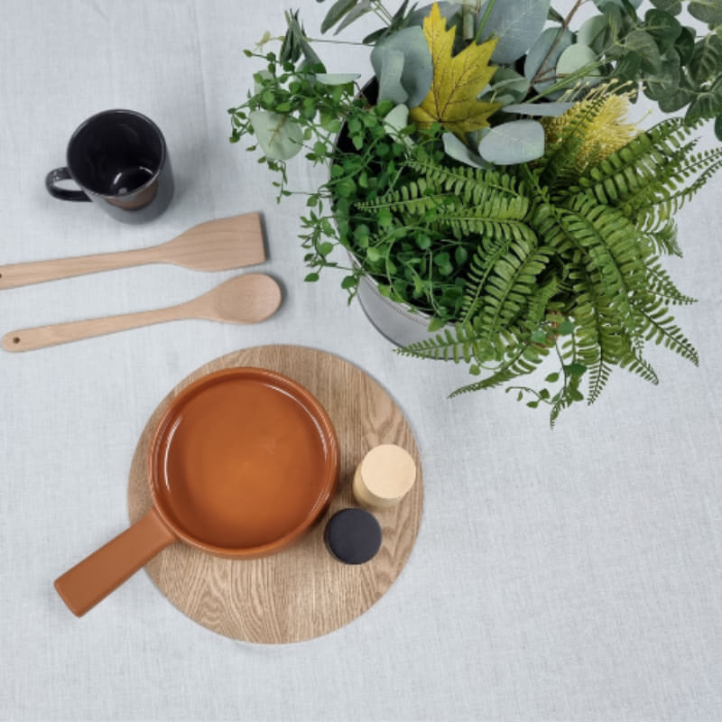 A table adorned with a pot of plants and kitchen things,  featuring a sophisticated RANS Venice Linen Mist Tablecloth.