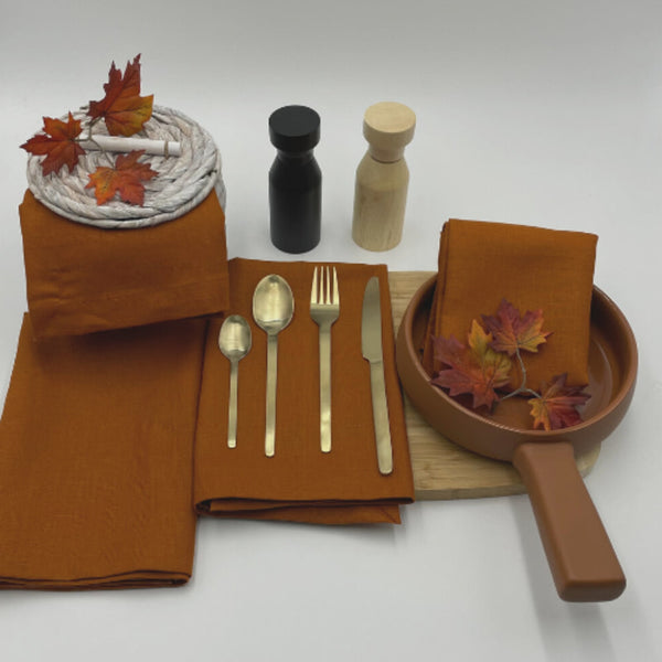 A dining table set with elegant Venice terracotta linen napkins, spoons, and forks, showcasing sophistication and practicality for any occasion.