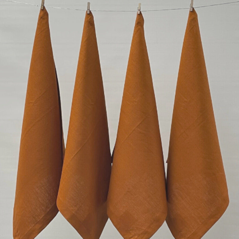 Four terracotta napkins hanging on a clothesline, exemplifying elegance and versatility in home textiles.