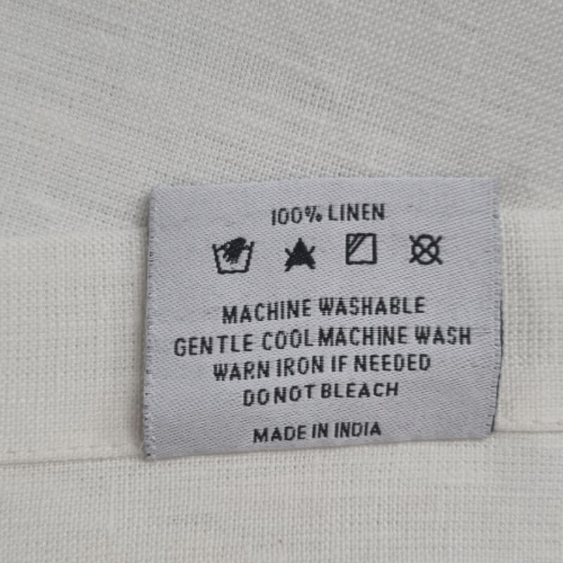 Back tag details of RANS Venice Linen White Tablecloth emphasizing practicality for effortless garment care.